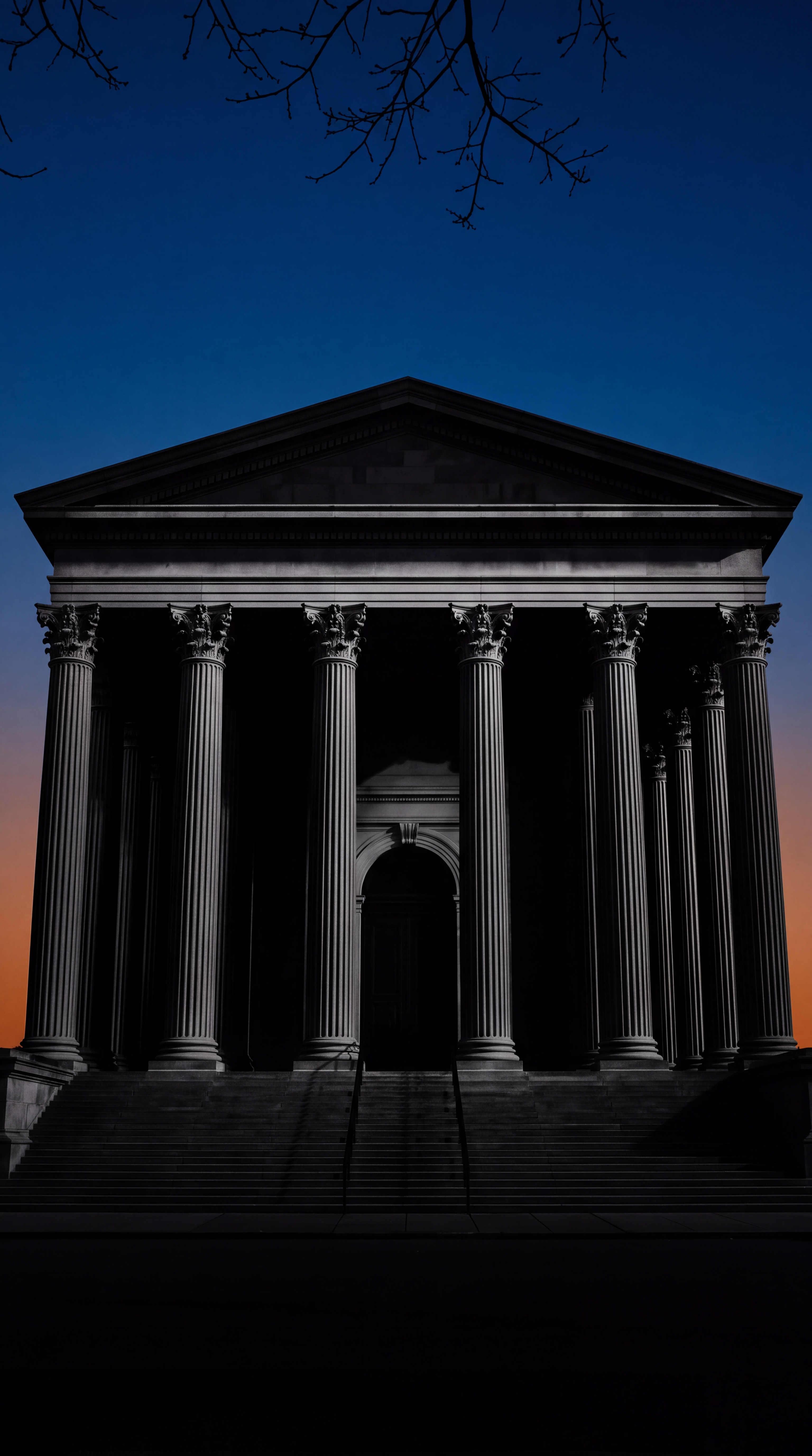 A silhouette of a classical building with columns against a twilight sky.