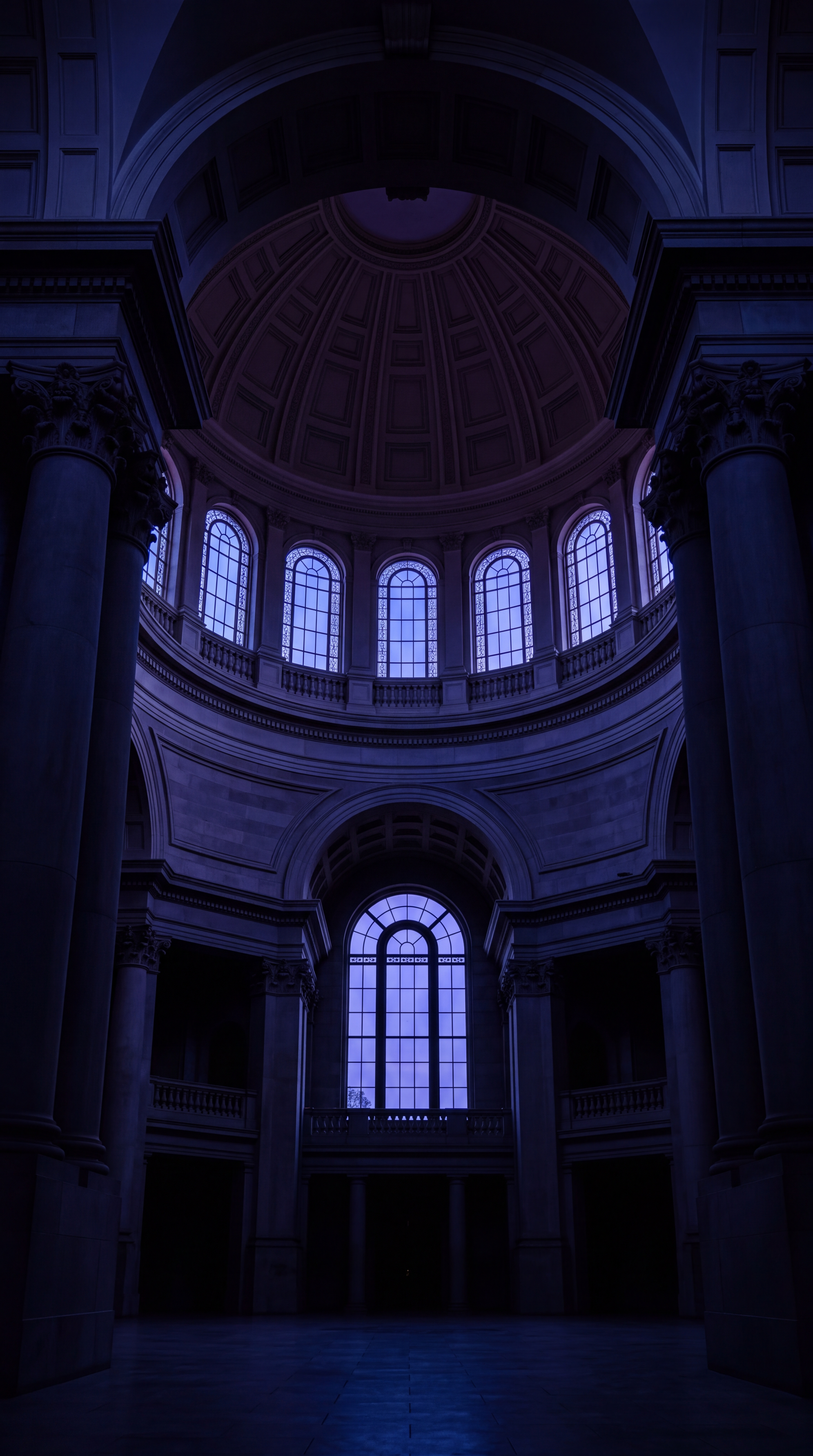 An interior view of a grand building featuring tall columns and large windows.