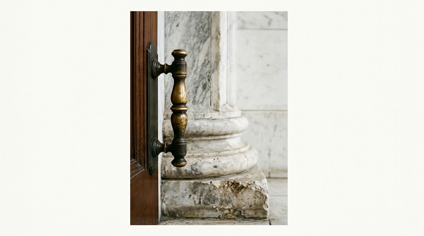 A close-up view of a door handle next to a marble column.