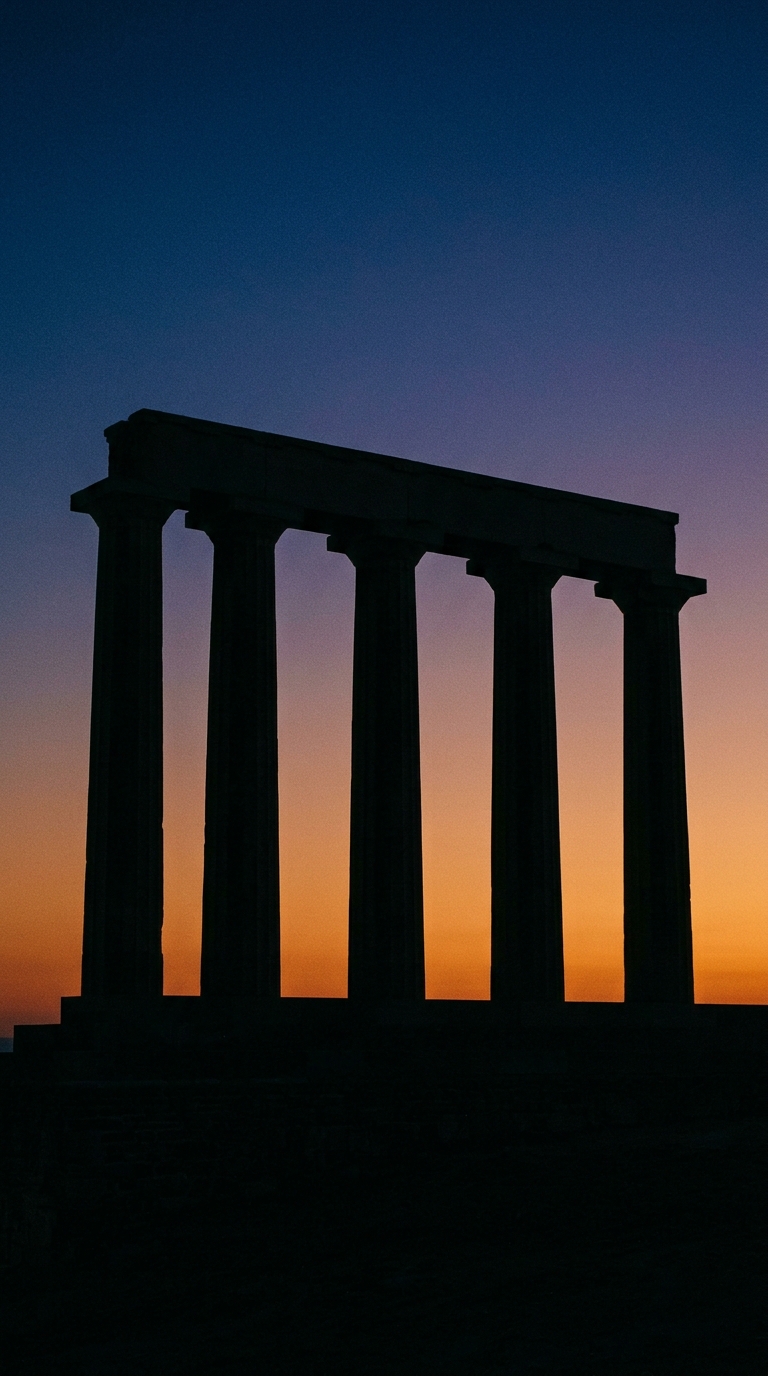 A silhouette of ancient columns against a sunset sky.