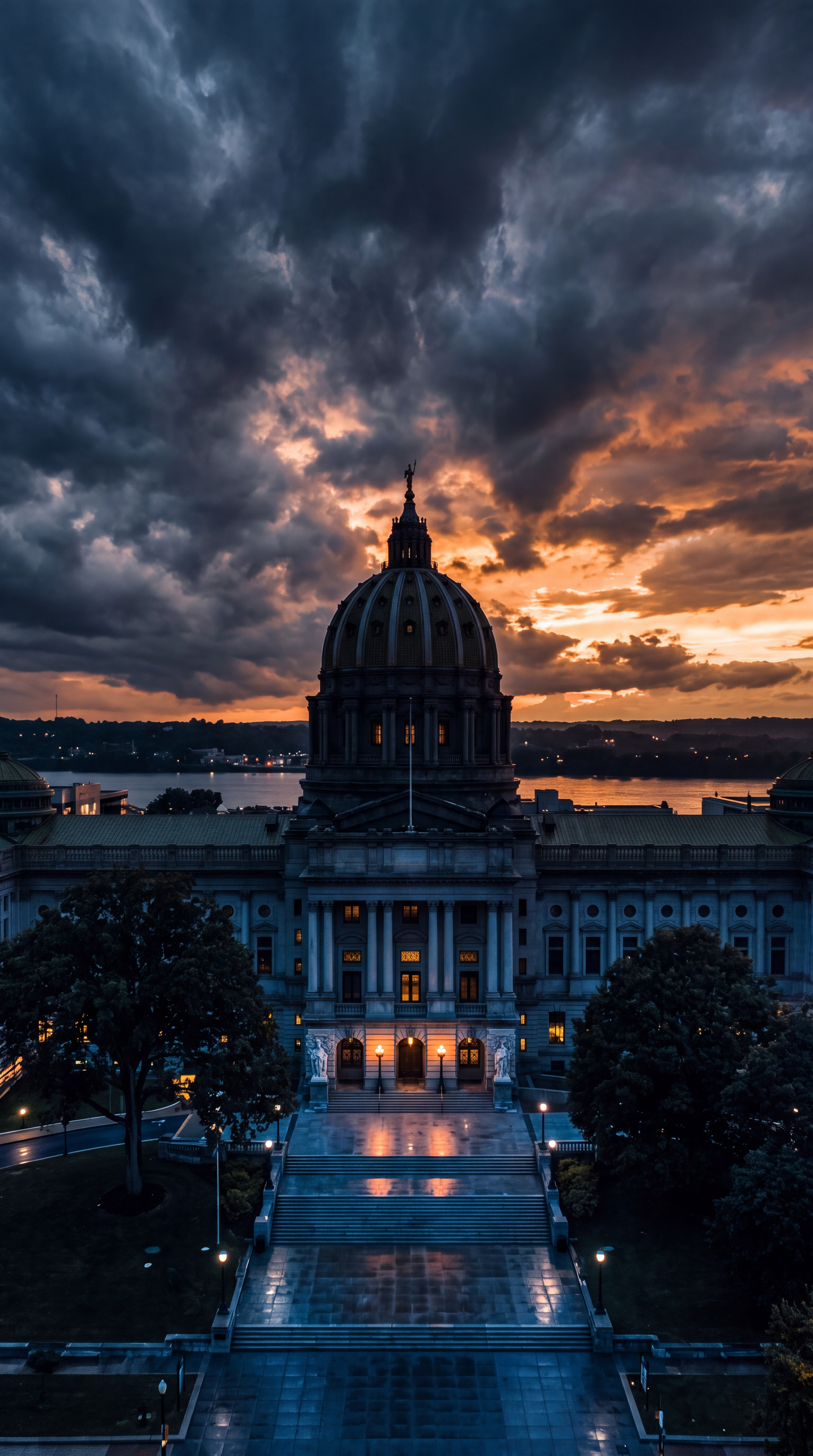 A historic building with a large dome is illuminated against a dramatic sunset sky.