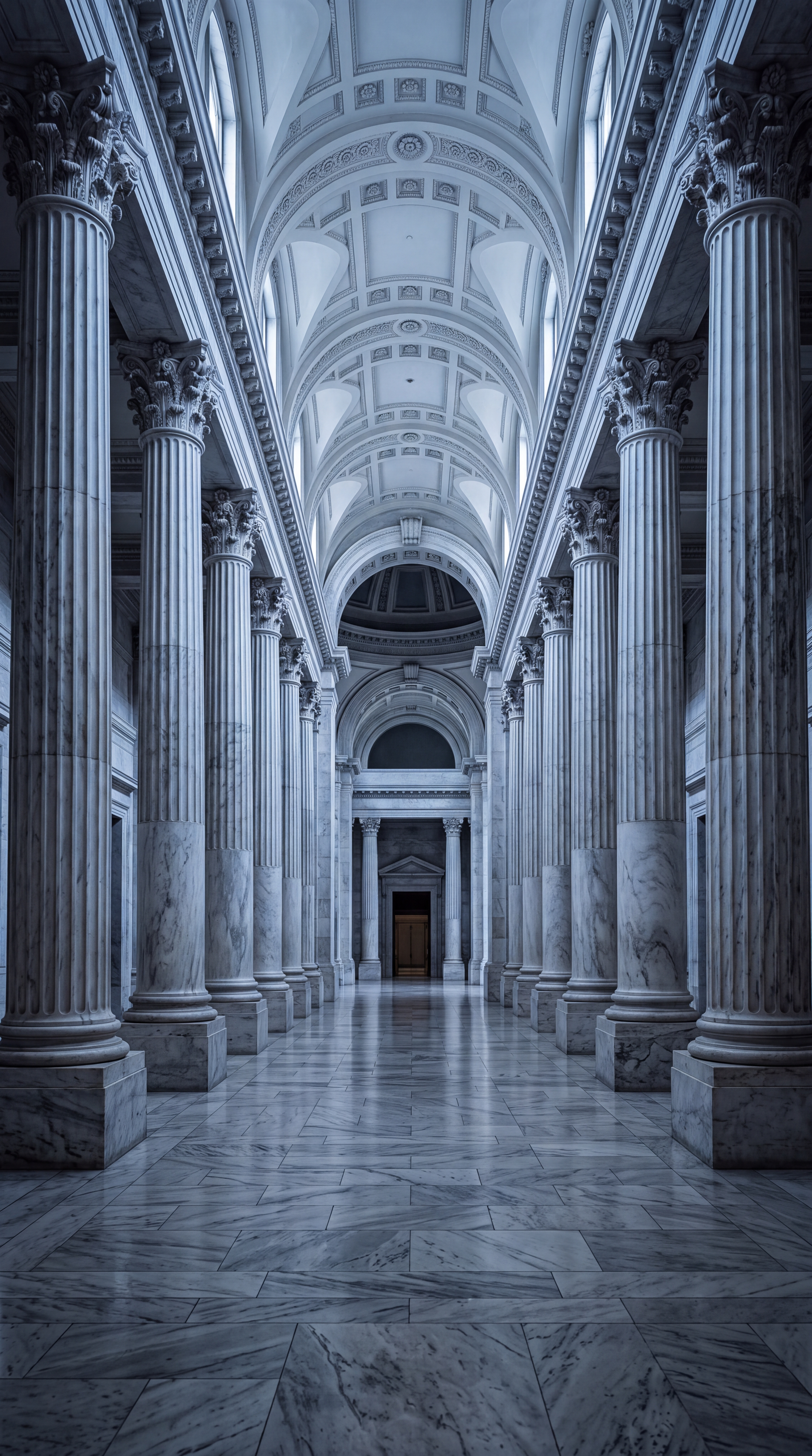 A grand interior hallway featuring tall marble columns and an ornate ceiling.