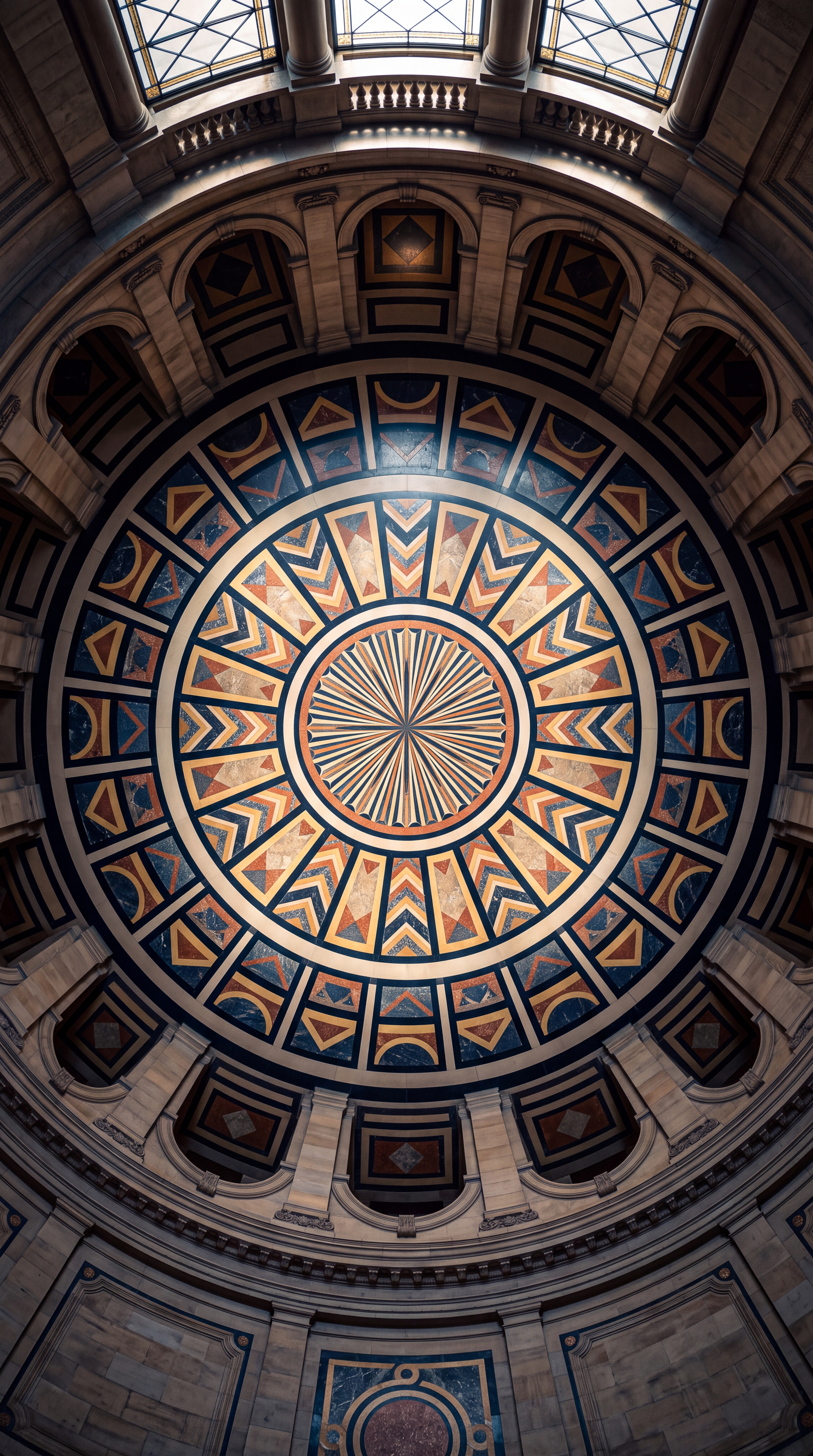 A detailed circular ceiling design featuring geometric patterns and vibrant colors.