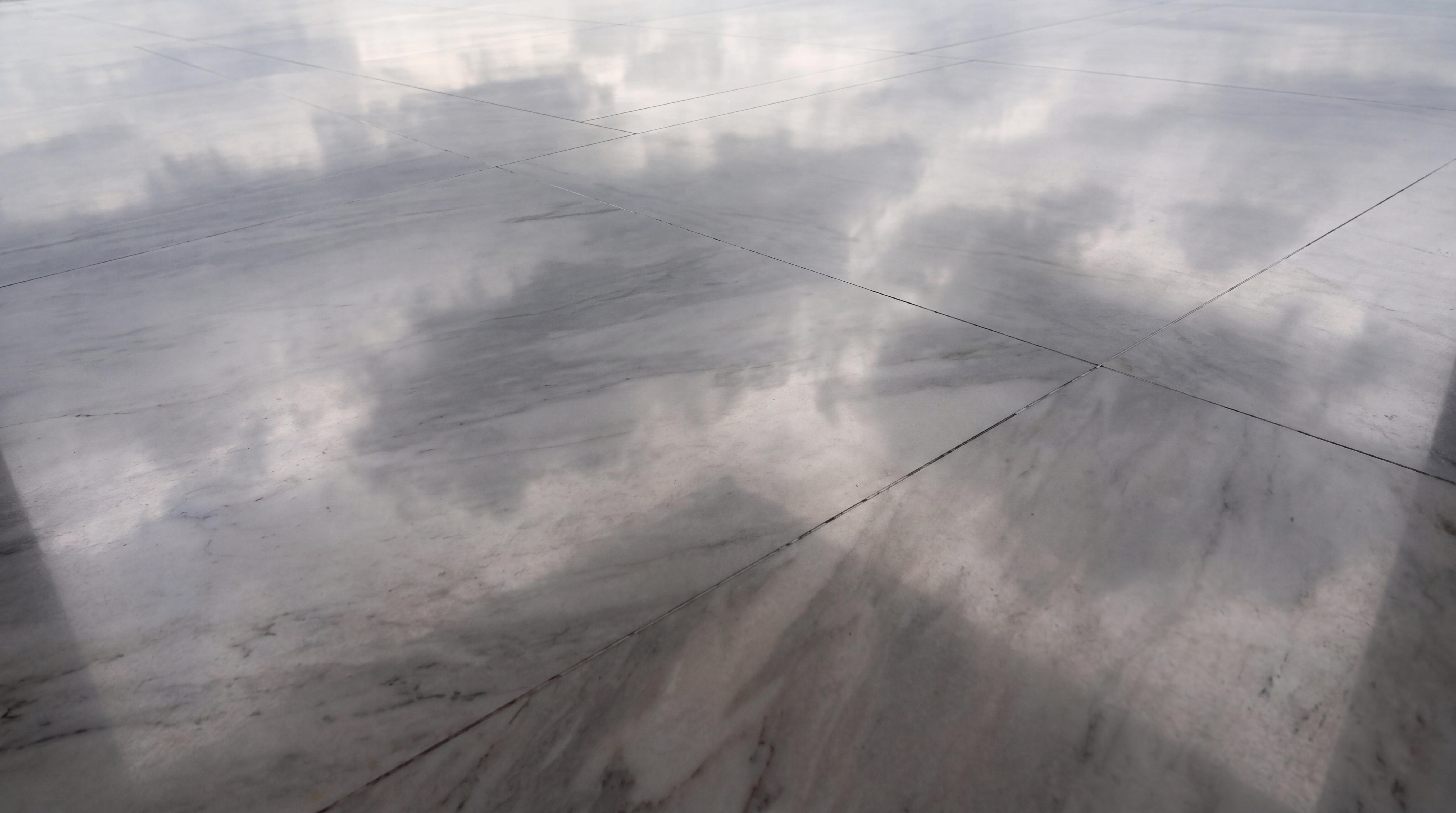 A polished marble floor reflecting clouds in the sky.