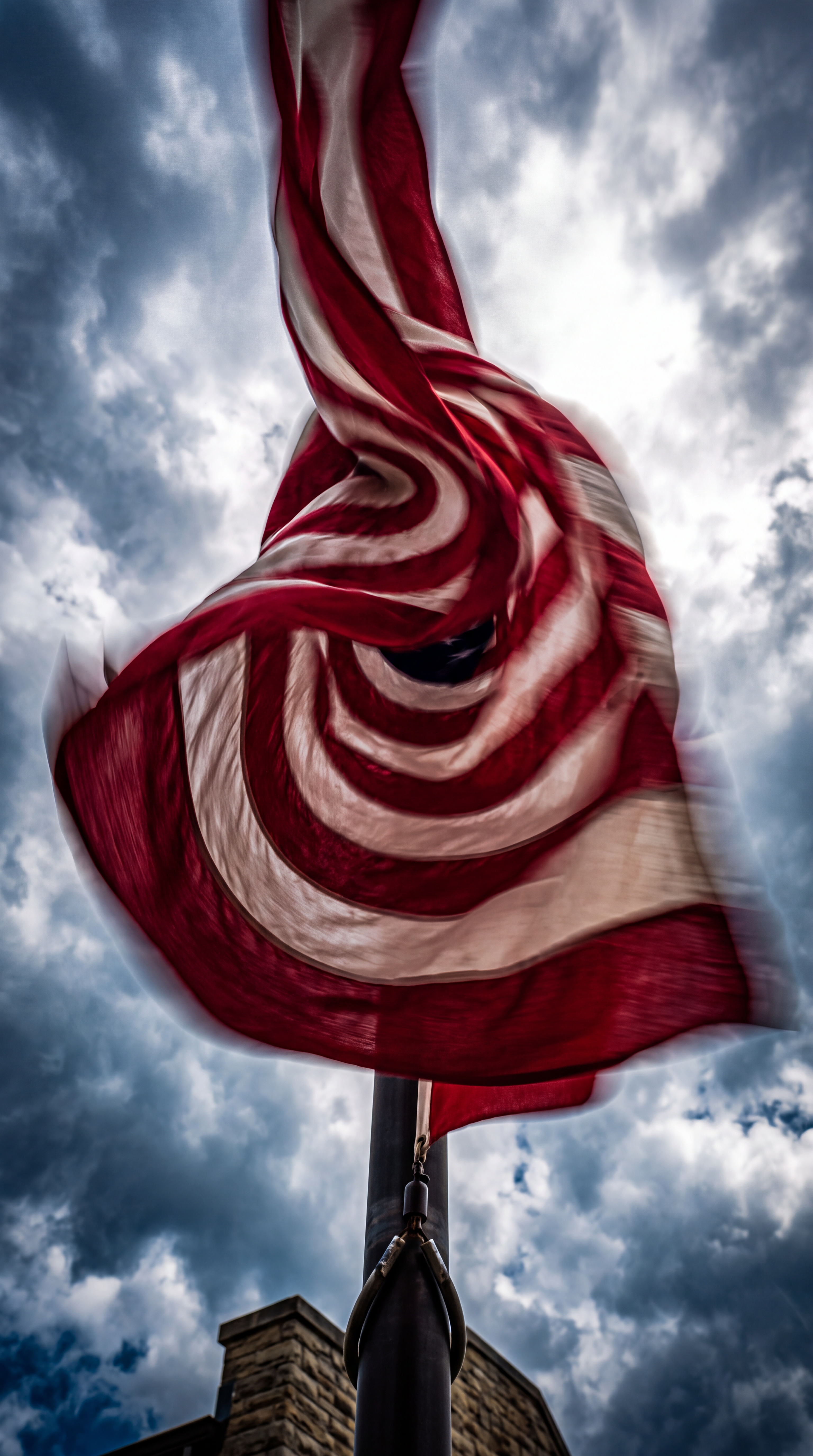 An American flag is waving against a cloudy sky.