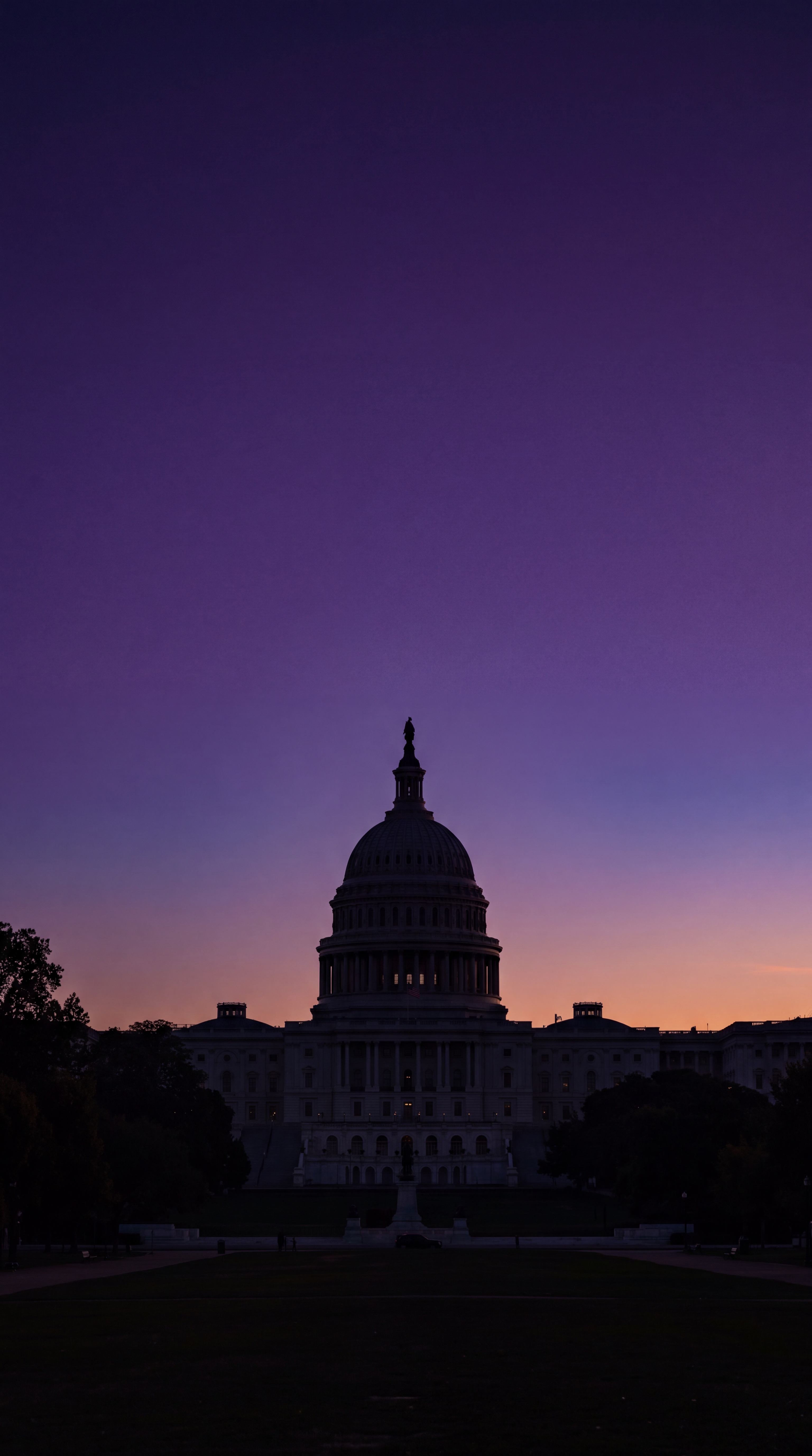 The silhouette of a large dome building against a purple sunset sky.