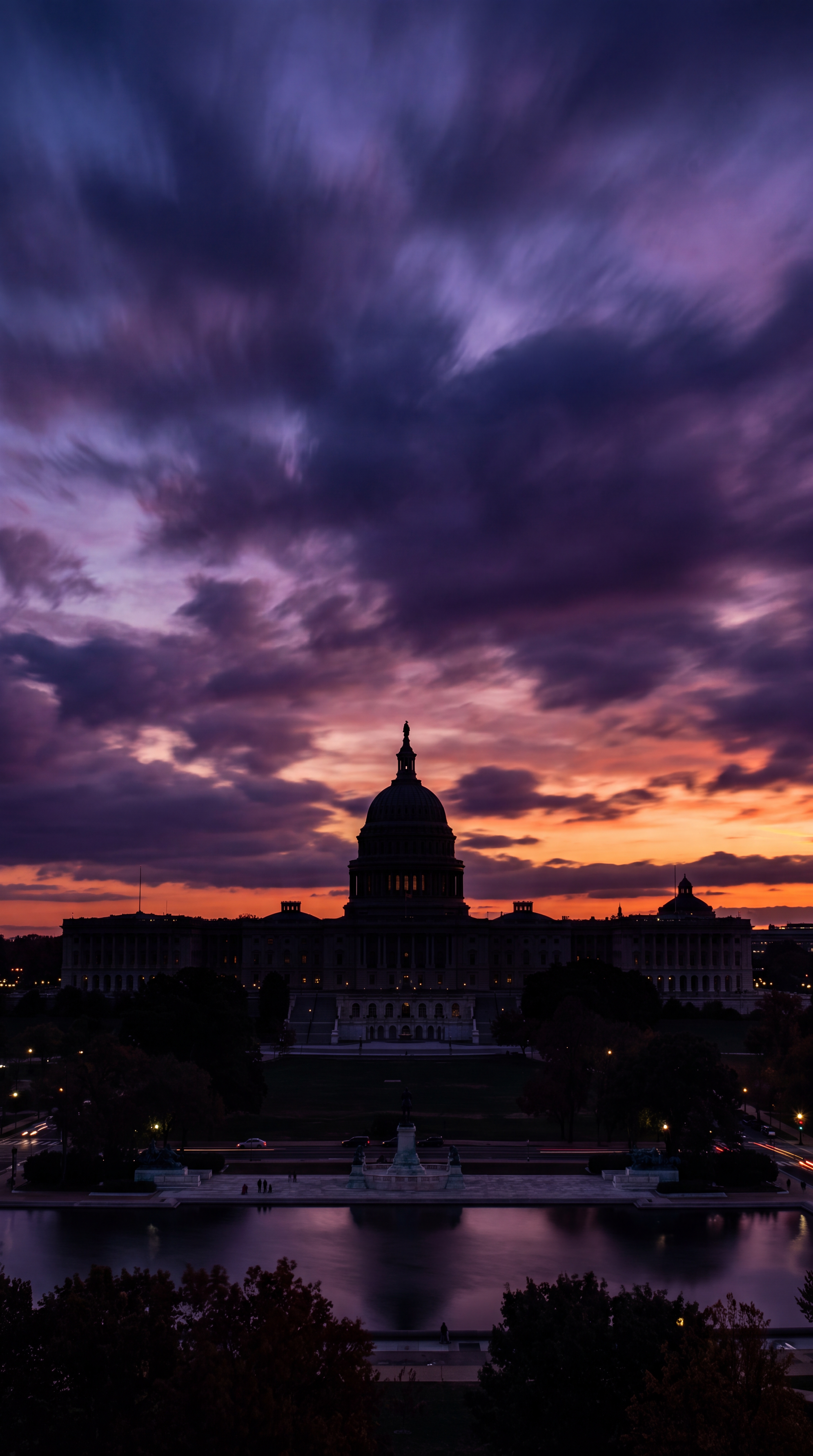A silhouette of a large dome building against a colorful sunset sky.