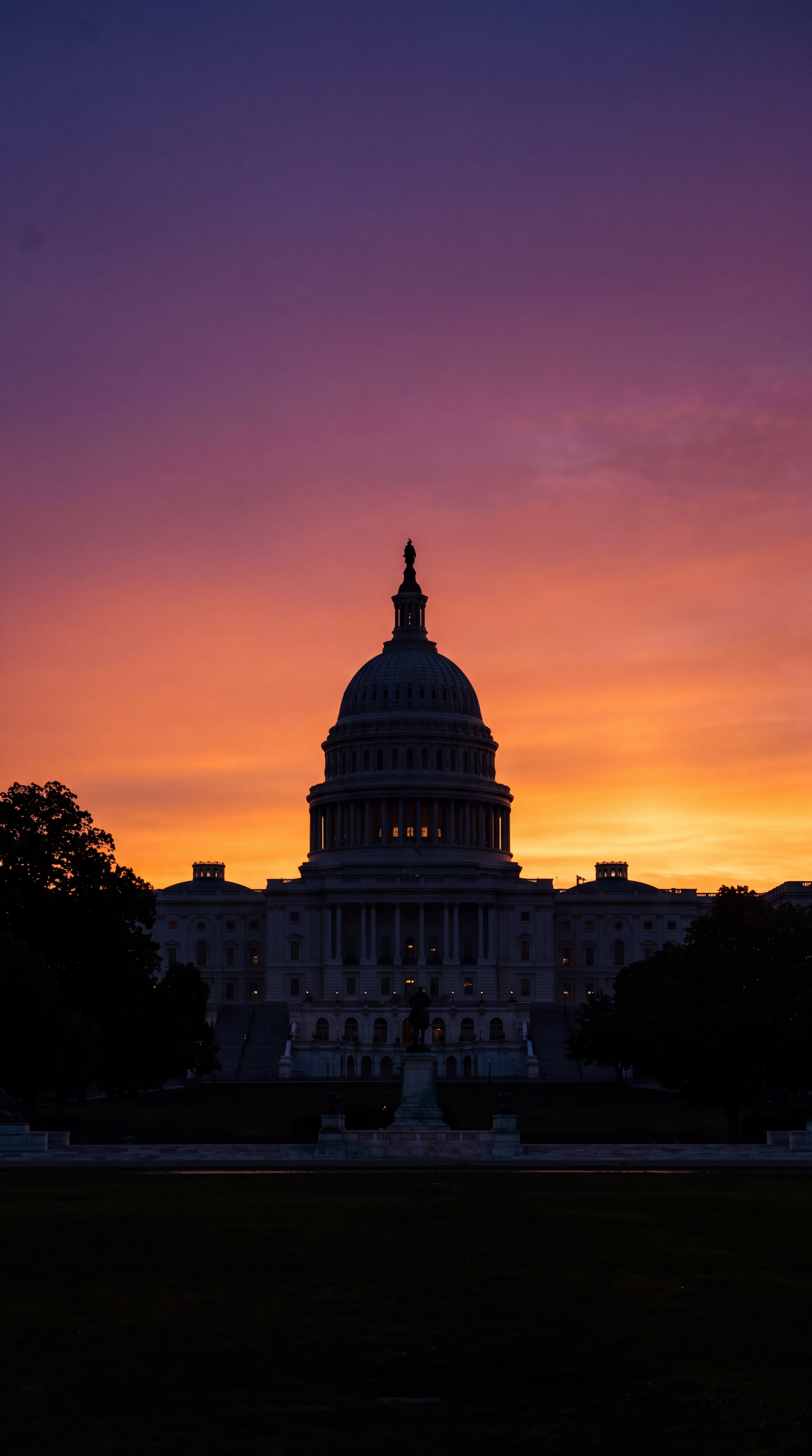 The silhouette of a large dome building against a colorful sunset sky.