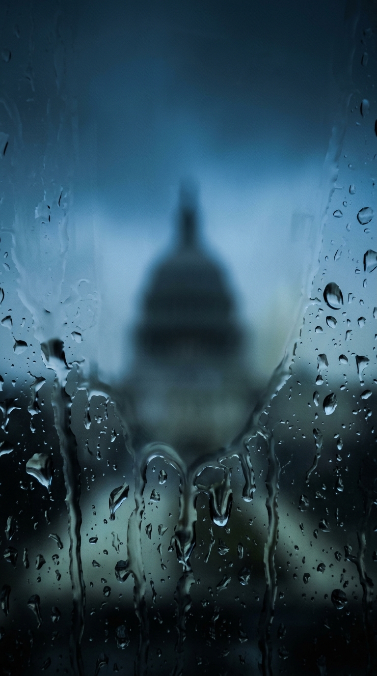 A blurred view of a dome structure through a rain-soaked window.