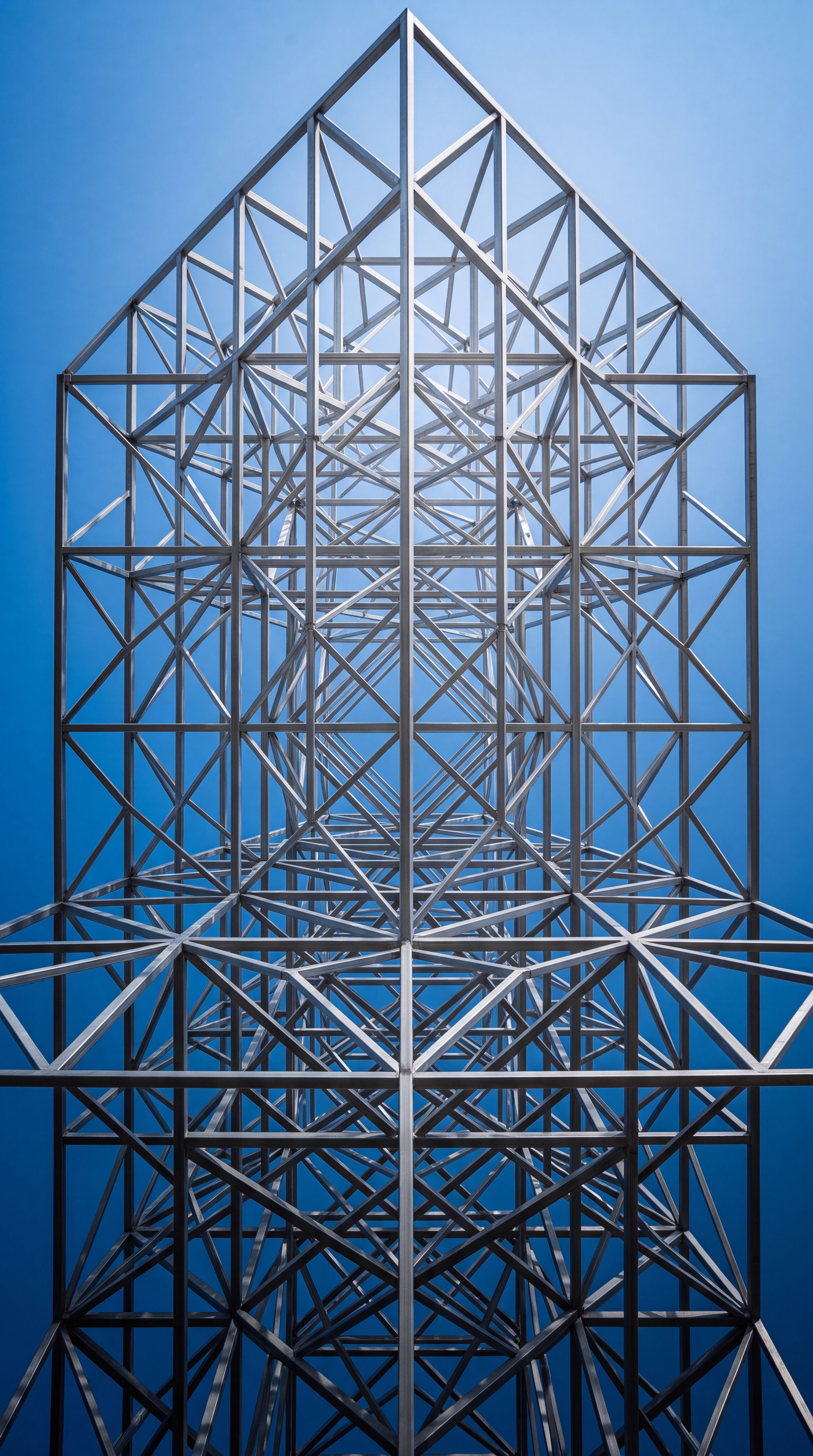 A geometric metal structure viewed from below against a blue sky.