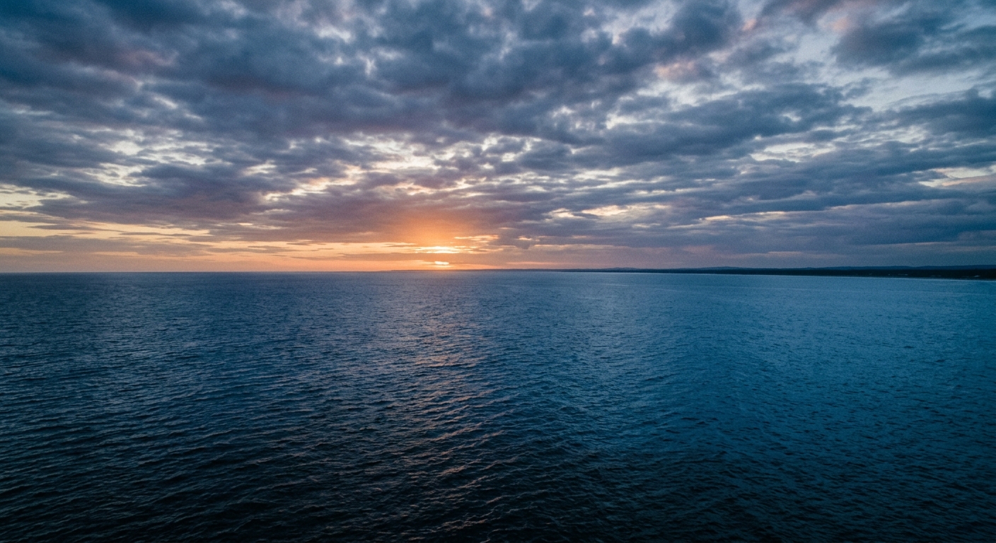 A serene view of the ocean at sunset with a cloudy sky.