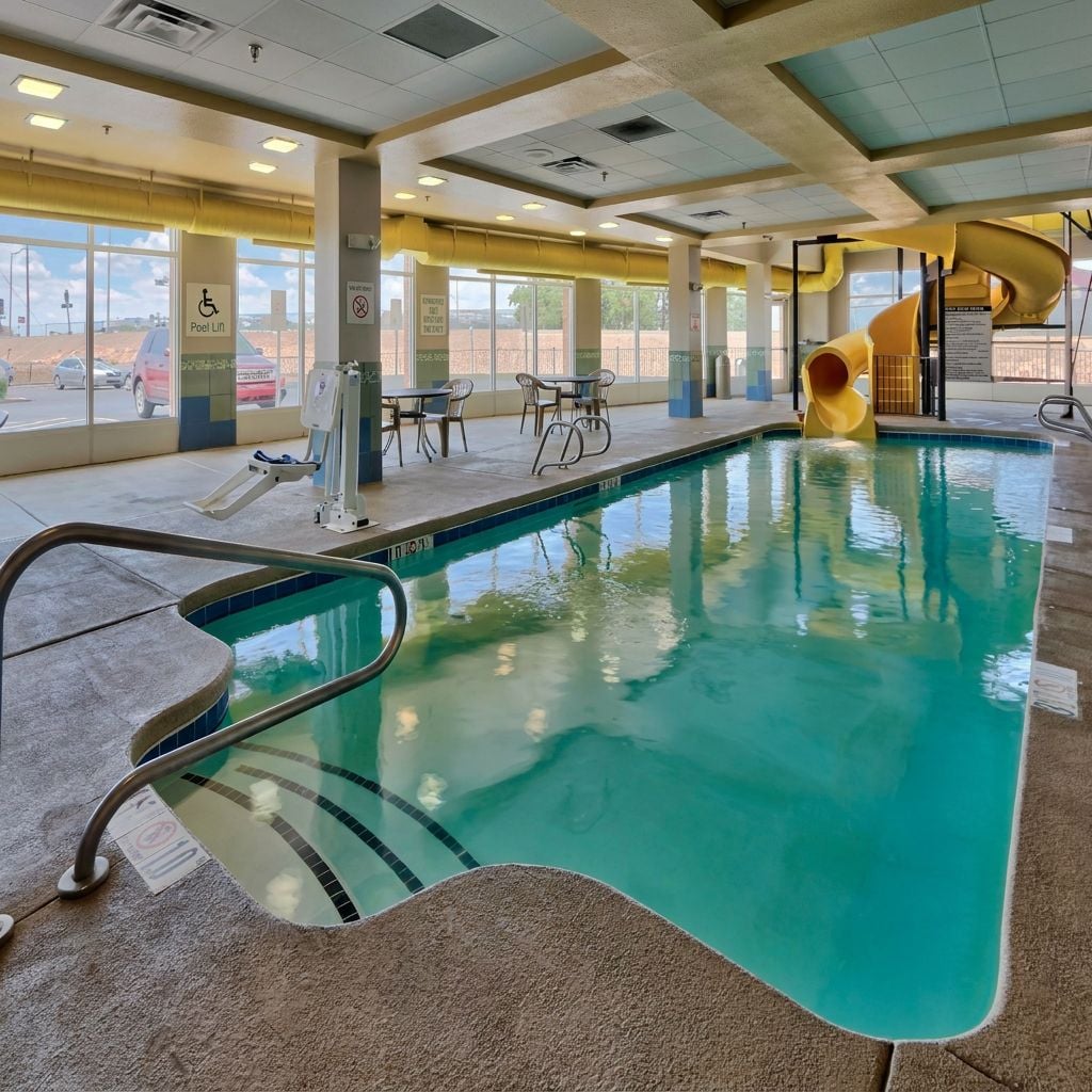 An indoor swimming pool area featuring a water slide and seating.