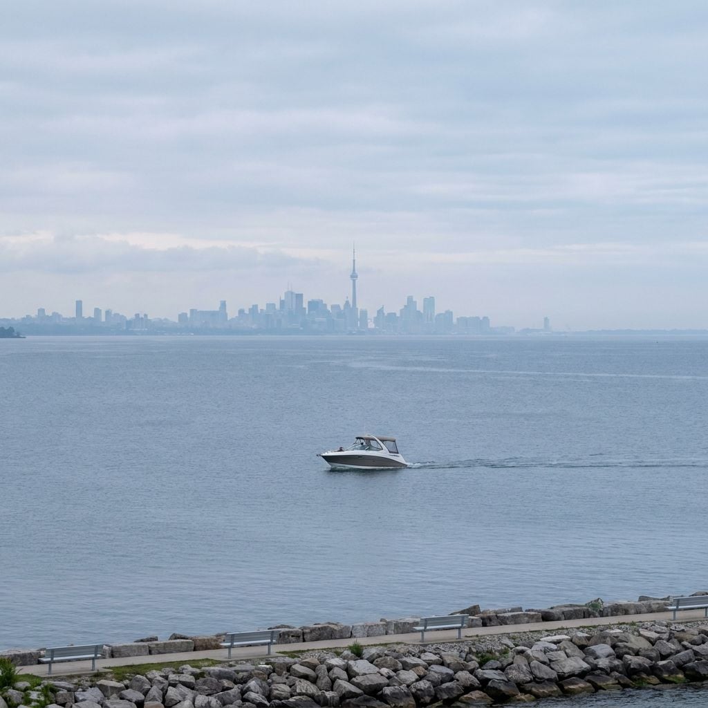 A boat is sailing on a body of water with a city skyline in the background.